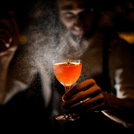 Professional bartender serving a cocktail with a lemon slice and Professional bartender serving a cocktail with a lemon slice and